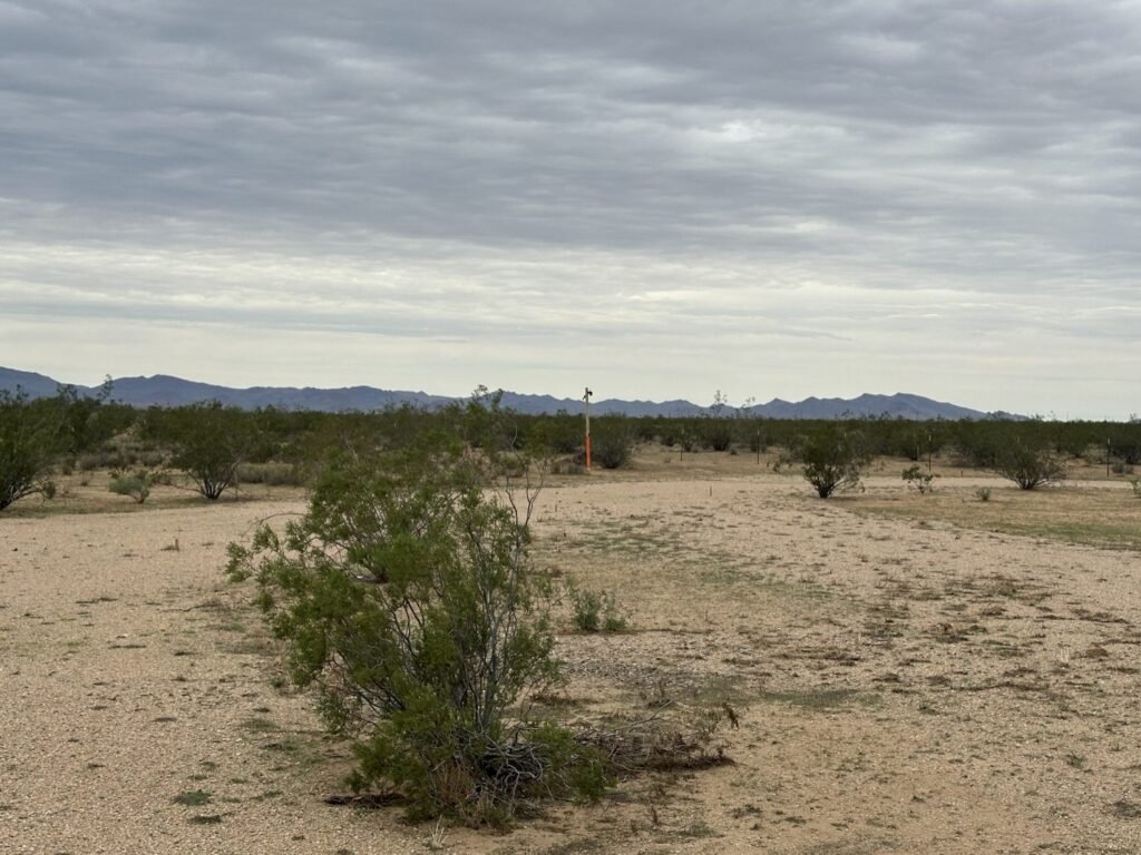 Open gravel lot with orange marker post at RV Safe Site, a snowbird RV stopover in Golden Valley, AZ